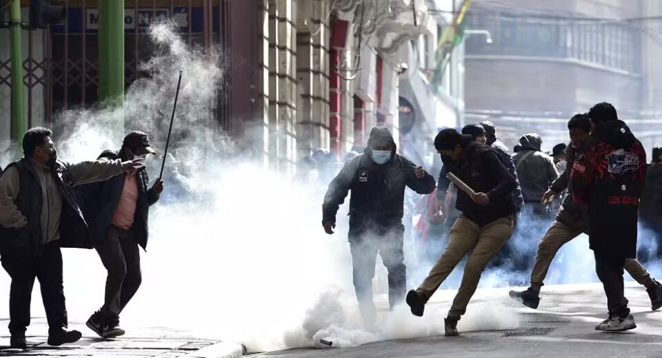 Manifestantes chutam bomba de gás lacrimogêneo lançada por policiais em meio a protestos em La Paz, na Bolívia — Foto: JORGE BERNAL / AFP