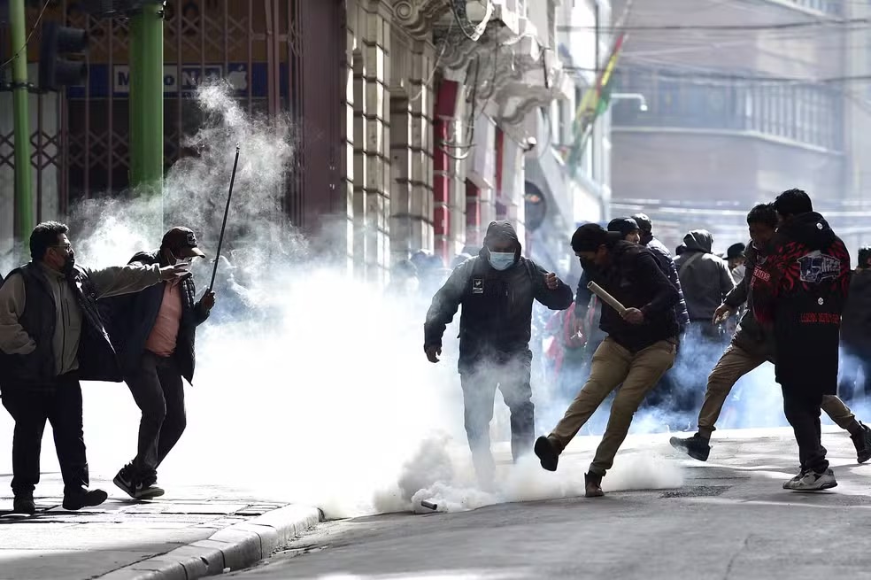 Manifestantes chutam bomba de gás lacrimogêneo lançada por policiais em meio a protestos em La Paz, na Bolívia — Foto: JORGE BERNAL / AFP