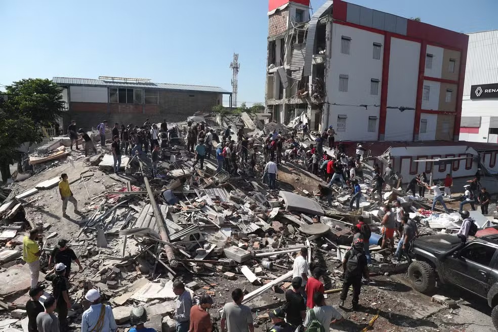 Equipes de resgate e moradores buscam por sobreviventes em escombros de prédio que colapsou em Cáli, na Colômbia, após terremoto de magnitude 7,4 que atingiu o país em 10 de agosto de 2026. — Foto: AP Photo/Santiago Saldarriaga